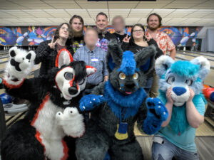 Group photo of fursuiters and other people at a bowling alley (some faces edited).